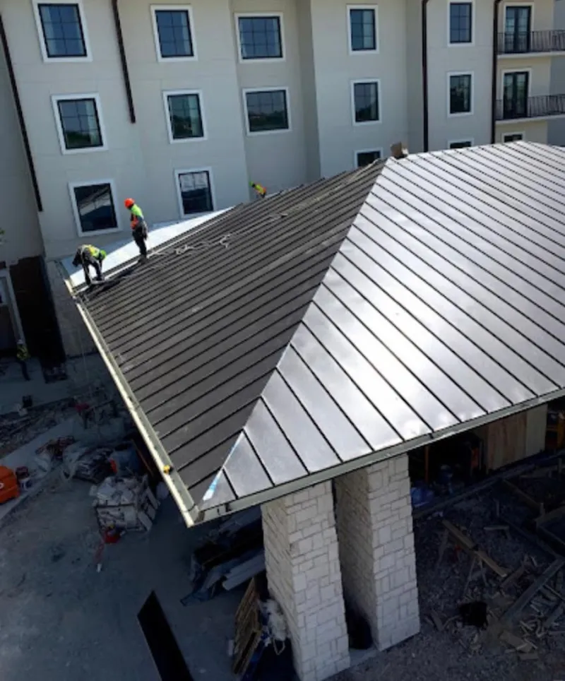 Crew installing standing seam metal roof panels on a commercial project in Dedham